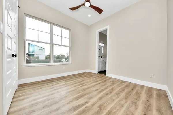 an empty room with wooden floor and ceiling fan
