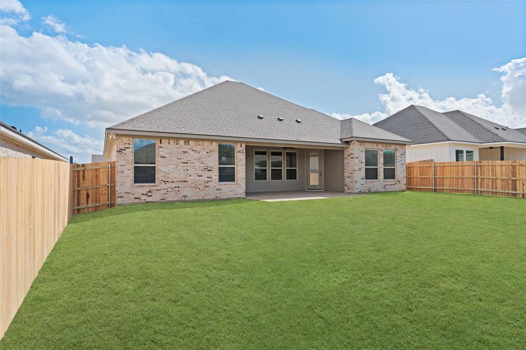 9824 Durango Trail Waco, TX 76712 - Photo 29 of 30 Expansive rear lawn featuring a privacy fence, brick exterior, multiple windows, and a covered patio area