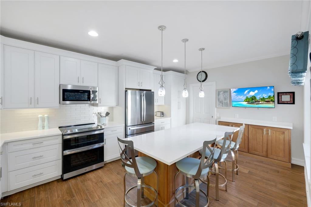 11426 Quail Village Way Naples, FL 34119 - Photo 11 of 46 a kitchen with stainless steel appliances a dining table chairs microwave and sink