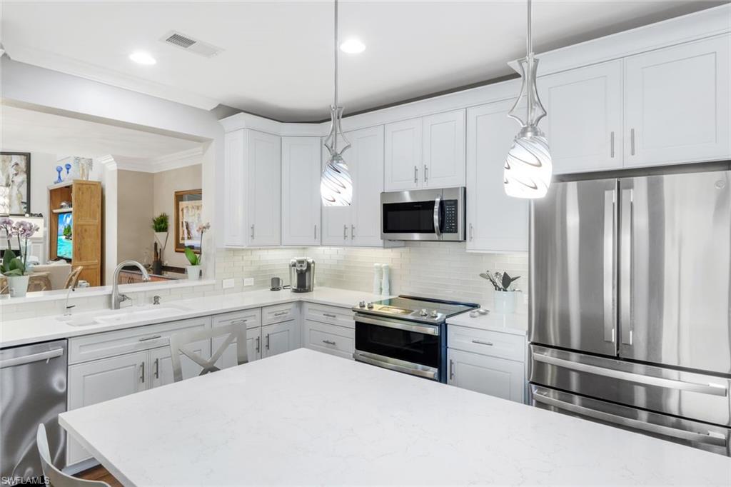 11426 Quail Village Way Naples, FL 34119 - Photo 12 of 46 a kitchen with a sink stainless steel appliances and white cabinets