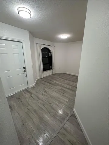 an empty room with wooden floor and entrance