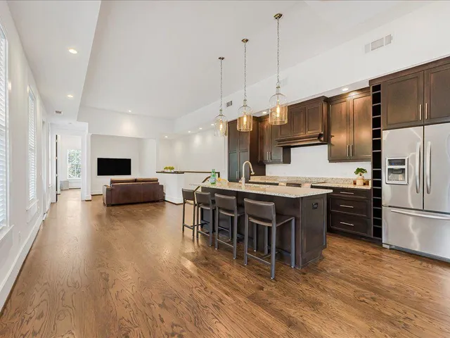 a kitchen with stainless steel appliances granite countertop a refrigerator a stove top oven a sink dishwasher and white cabinets with wooden floor