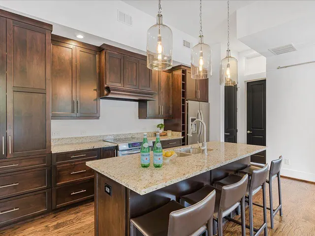 a kitchen with granite countertop a sink cabinets and stainless steel appliances