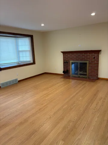 an empty room with wooden floor fireplace and windows