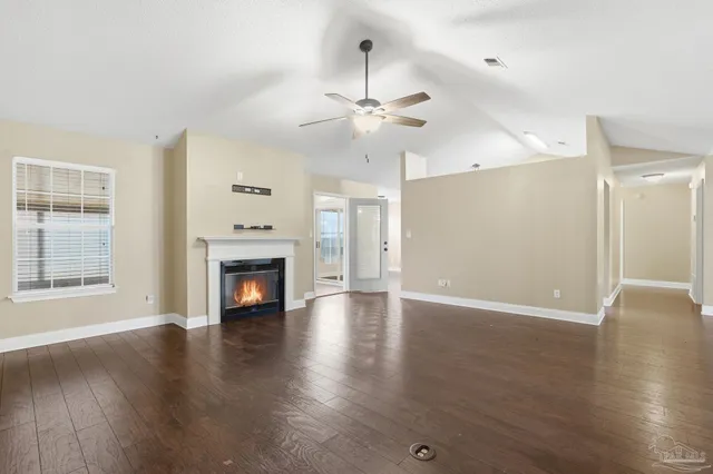 an empty room with wooden floor fireplace and windows