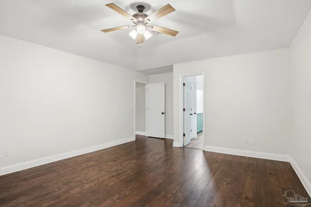 an empty room with wooden floor and ceiling fan