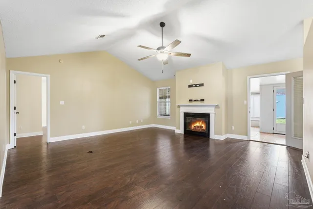 a view of an empty room with wooden floor fireplace and a window