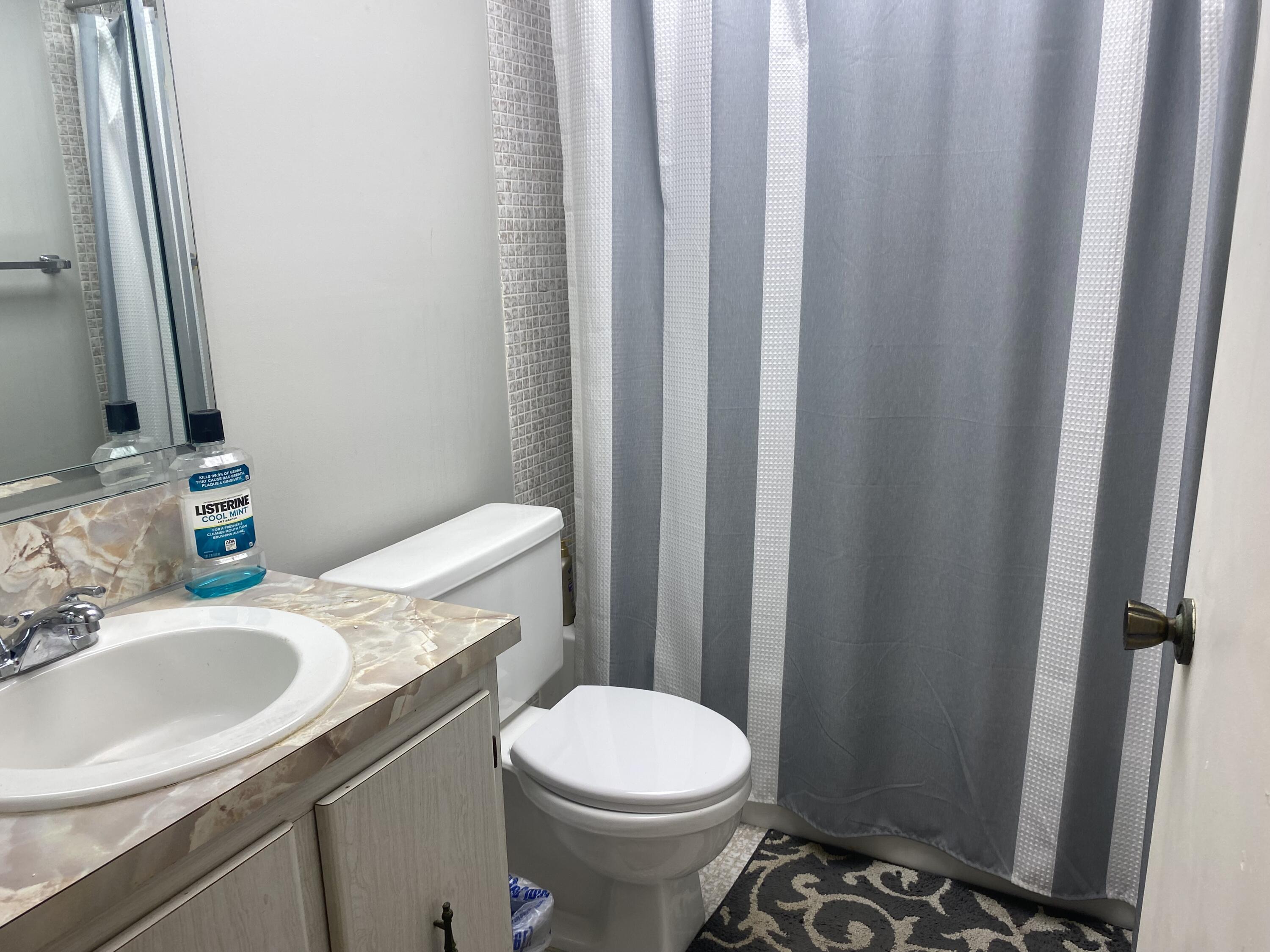 542 Normandy Lane, Unit 542 NORMANDY L Delray Beach, FL 33484 - Photo 20 of 41 a bathroom with a sink a toilet a mirror and shower curtain
