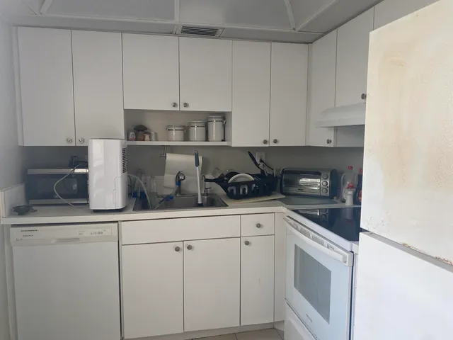 a kitchen with white cabinets and white appliances