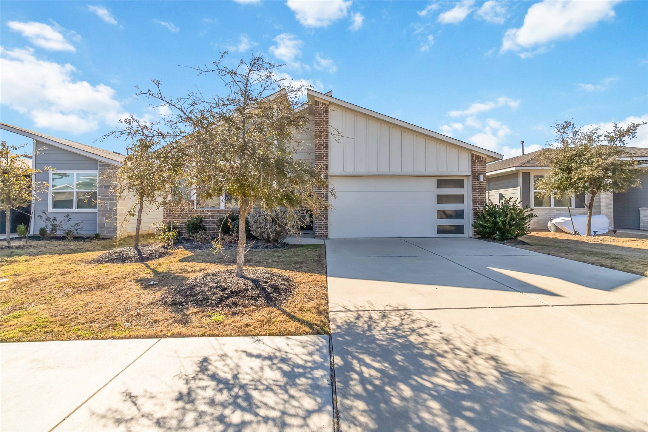 217 Deserti Road Leander, TX 78641 - Photo 4 of 31 Mid-century home featuring brick siding, driveway, board and batten siding, and an attached garage