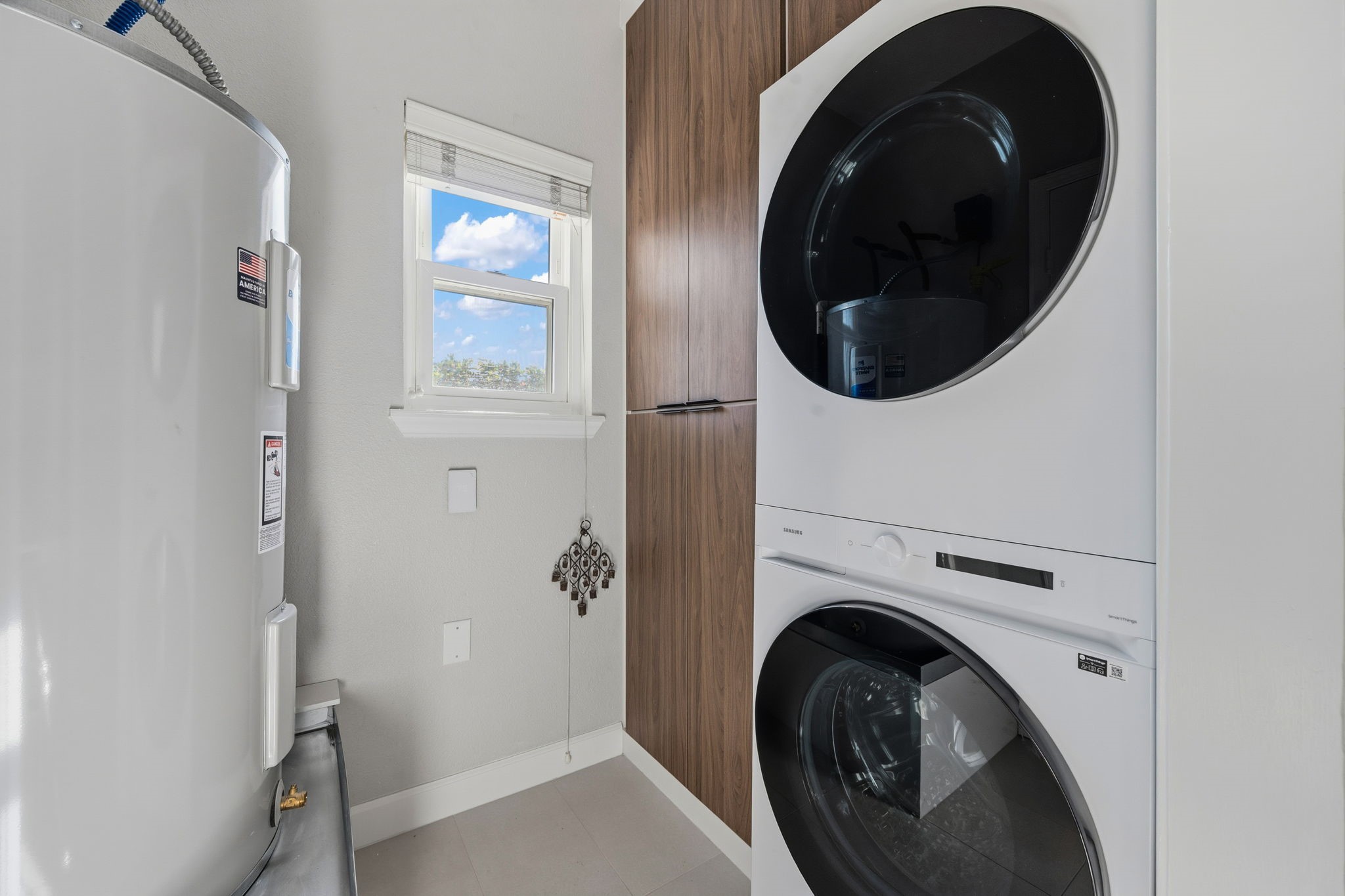 1831 Palm Street Houston, TX 77004 - Photo 19 of 27 Efficient laundry room with a stacked washer and dryer, a water heater, and a small window for natural light.