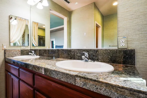 a bathroom with a granite countertop sink and a mirror