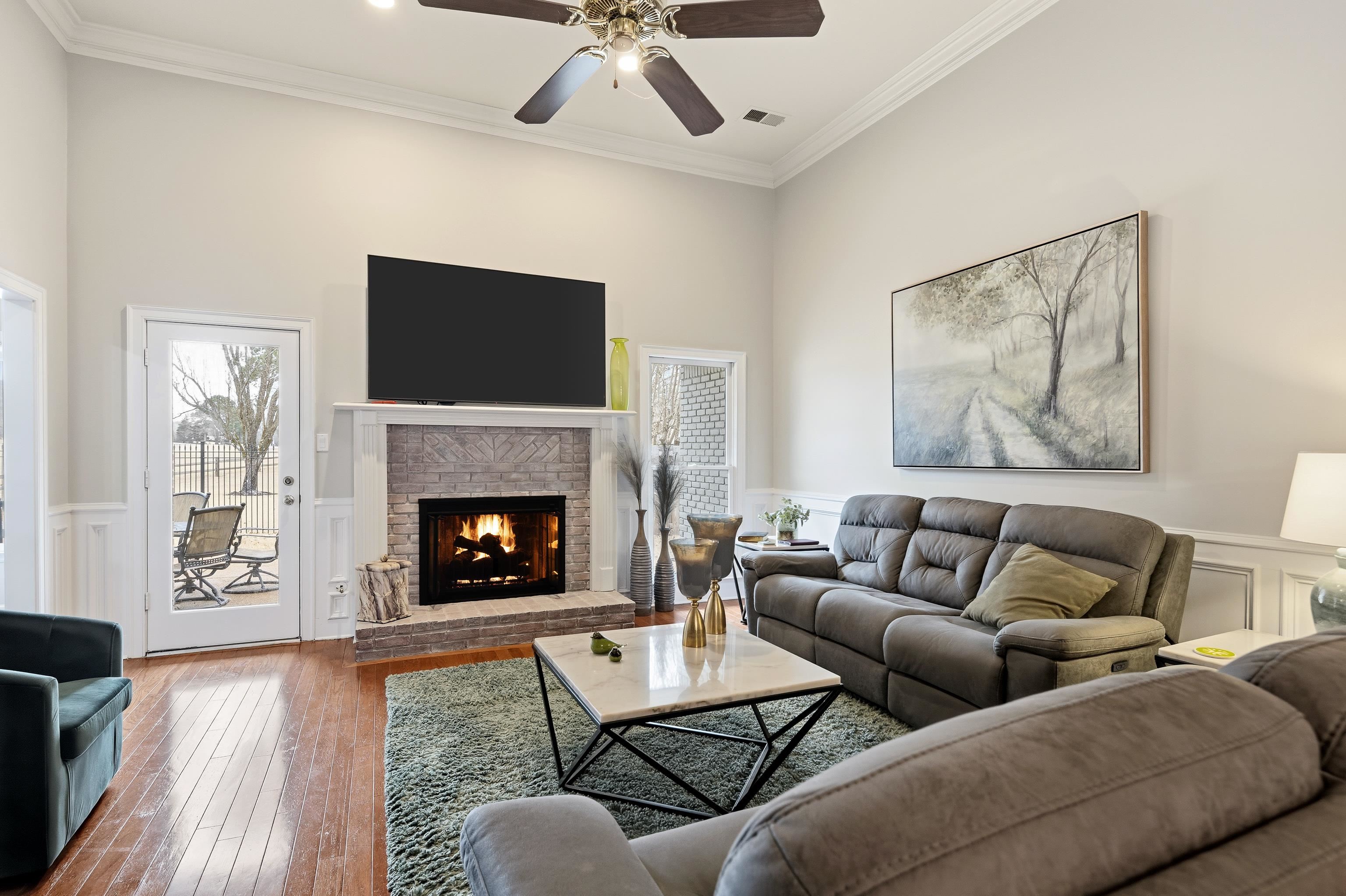 10281 Peyton Path Cove Collierville, TN 38017 - Photo 20 of 40 Living room with a decorative wall, a wainscoted wall, a brick fireplace, crown molding, and hardwood / wood-style floors