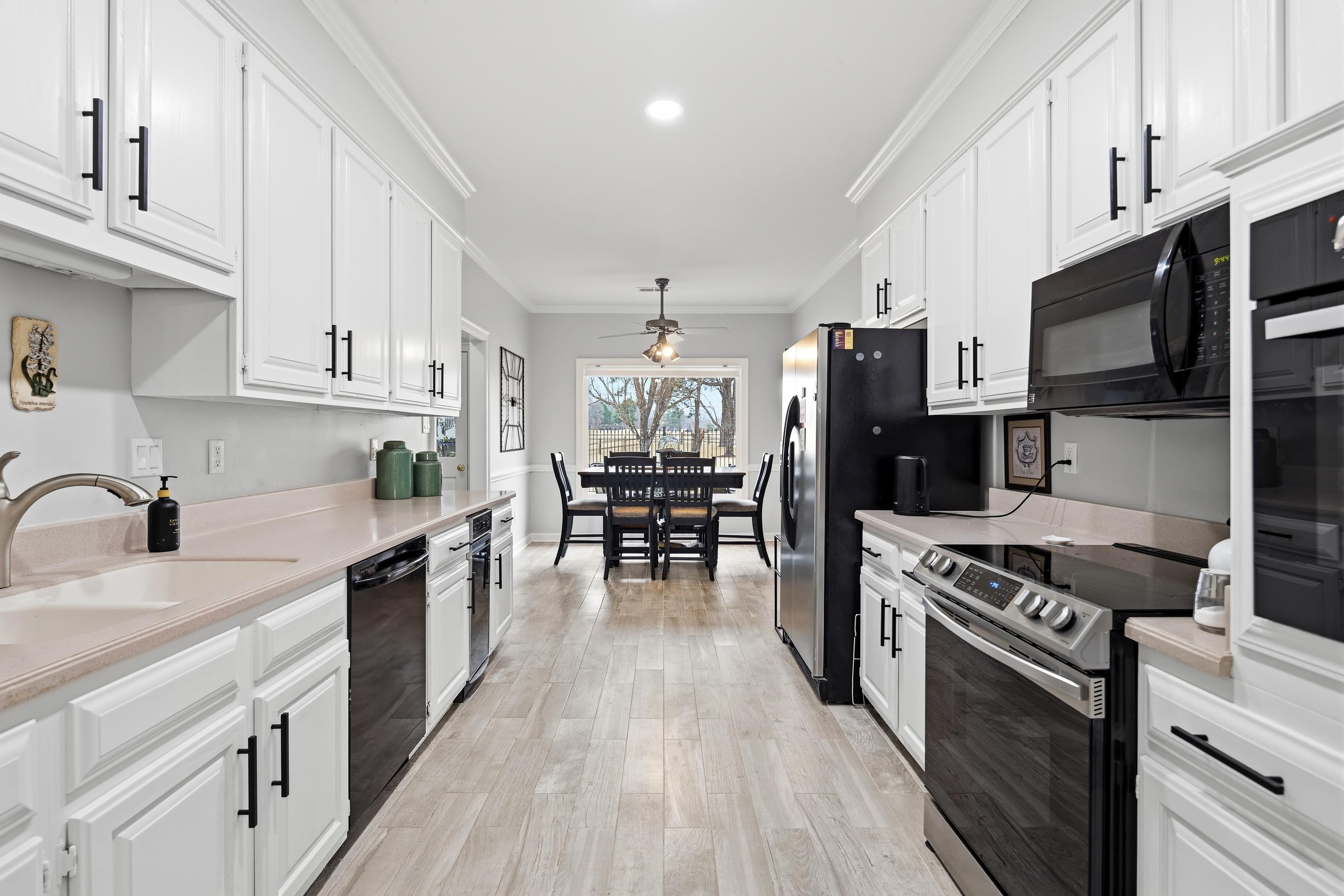 10281 Peyton Path Cove Collierville, TN 38017 - Photo 23 of 40 Kitchen featuring crown molding, white cabinets, black appliances, and light countertops