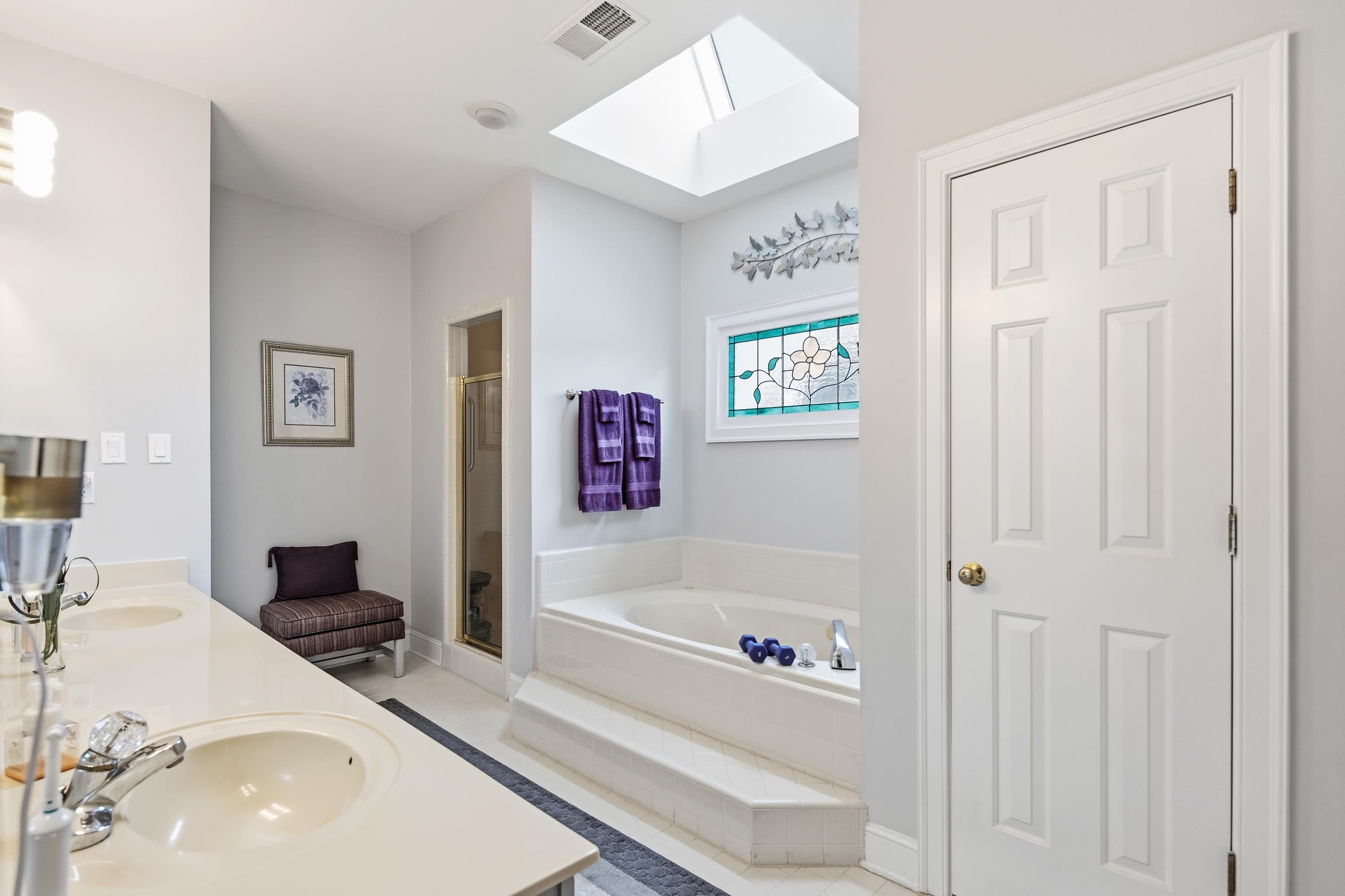 10281 Peyton Path Cove Collierville, TN 38017 - Photo 38 of 40 Bathroom featuring a skylight, a shower stall, double vanity, a bath, and light tile patterned floors