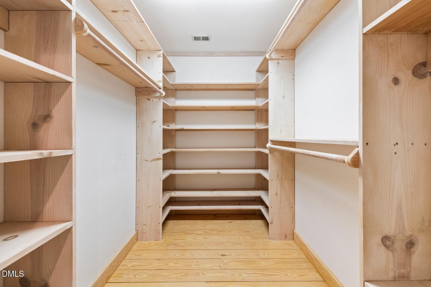 7391 Howerton Road Elon, NC 27244 - Photo 38 of 53 Walk-in closet featuring extensive built-in shelving, multiple hanging rods, and wood-finish flooring