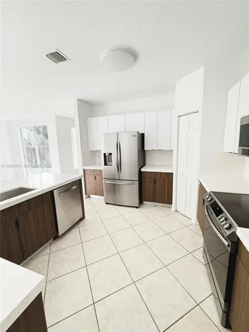 a kitchen with granite countertop a refrigerator and a stove top oven