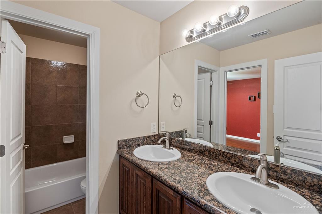 2806 San Ricardo Street Mission, TX 78572 - Photo 16 of 29 a bathroom with a granite countertop sink a mirror a shower and a bathtub