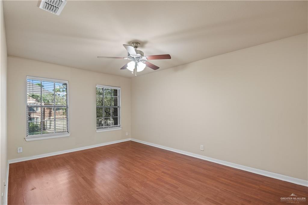 2806 San Ricardo Street Mission, TX 78572 - Photo 20 of 29 an empty room with wooden floor chandelier fan and windows