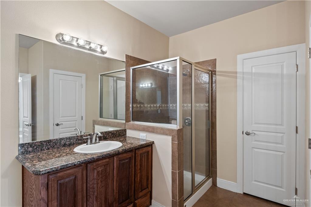 2806 San Ricardo Street Mission, TX 78572 - Photo 23 of 29 a bathroom with a granite countertop sink a large mirror and a shower