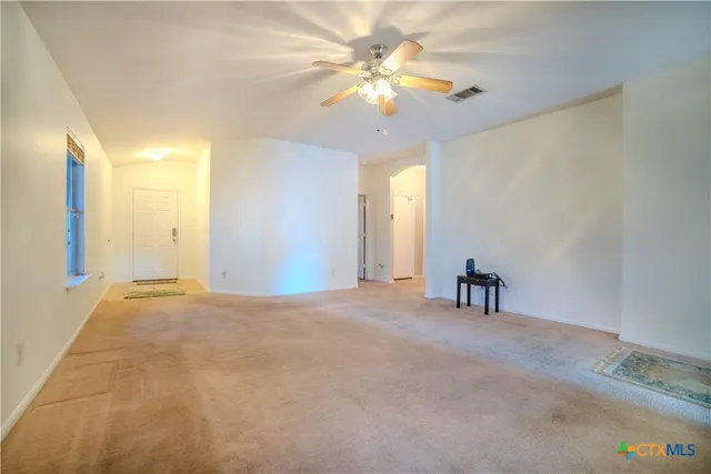 a view of an empty room with a chandelier fan