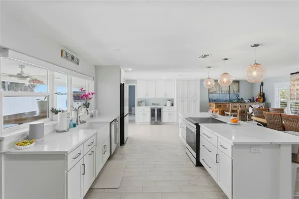 a kitchen that has a lot of white cabinets and stainless steel appliances