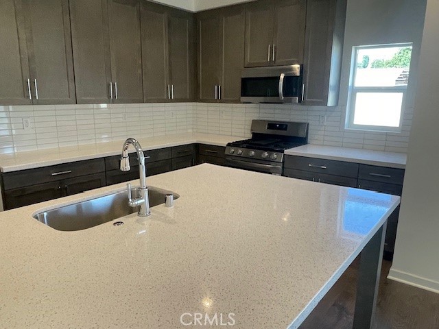 31960 Chagall Way Yucaipa, CA 92399 - Photo 7 of 12 a kitchen with a sink a microwave a stove and cabinets
