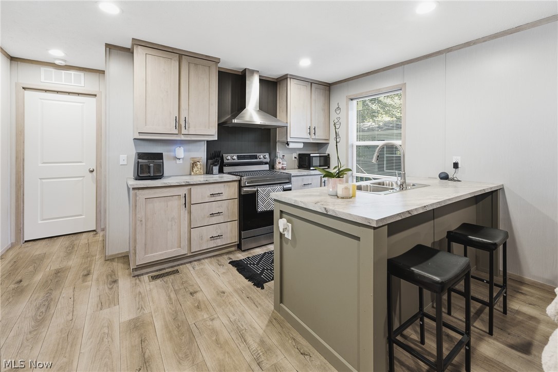4516 Navarre Road Southwest, Unit 13 Canton, OH 44706 - Photo 6 of 30 Kitchen featuring wood-finish flooring, two-tone cabinetry, stainless steel appliances, a center island with a sink, and recessed lighting