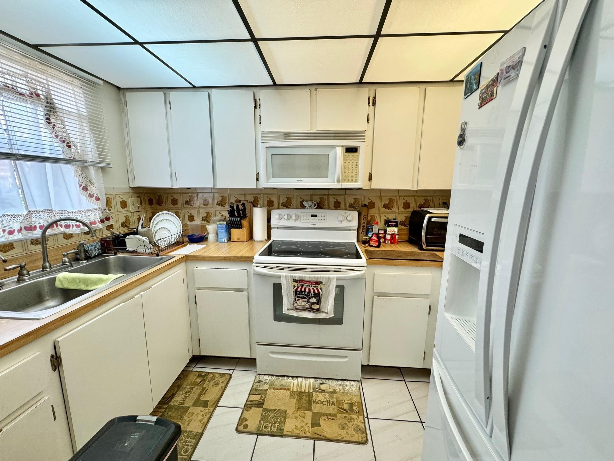 4357 West 11th Lane, Unit 55 Hialeah, FL 33012 - Photo 4 of 17 a kitchen with a stove a sink and a refrigerator