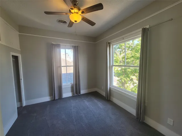 a view of an empty room with window and a kitchen