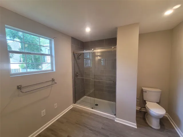 an empty room with wooden floor ceiling fan and window