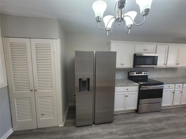 a kitchen with granite countertop a sink cabinets and stainless steel appliances
