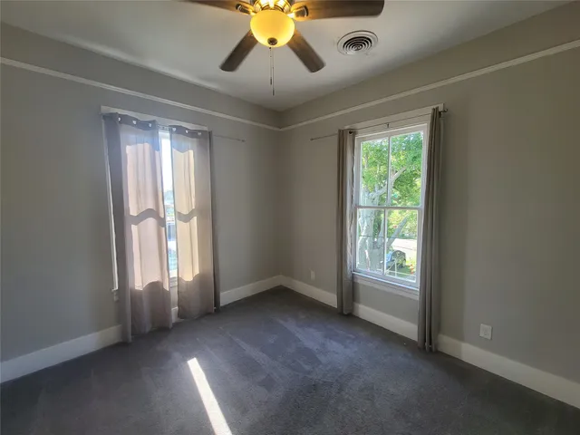 an empty room with windows and chandelier fan