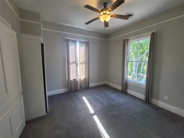 an empty room with windows and chandelier fan