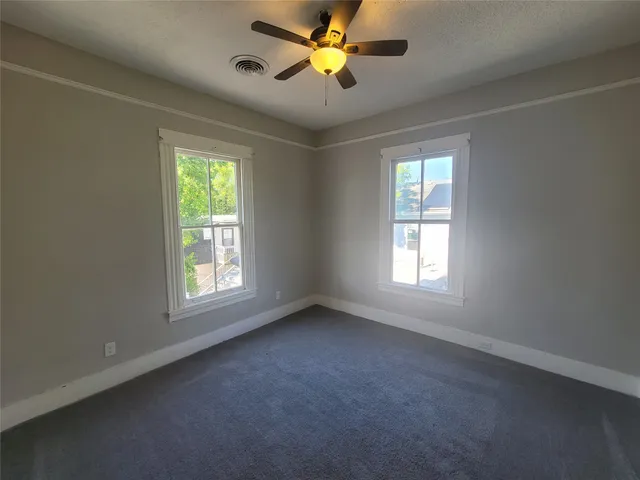 an empty room with windows and a ceiling fan
