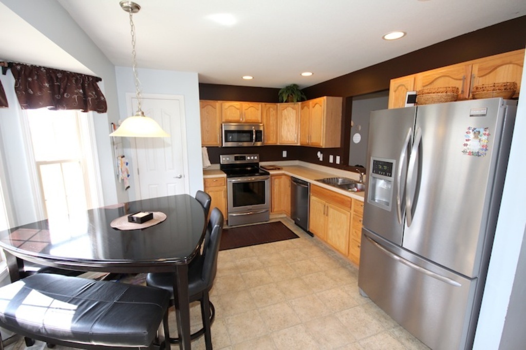 806 Cobblefield Road Champaign, IL 61822 - Photo 6 of 20 a kitchen with stainless steel appliances granite countertop a refrigerator a stove a sink a dining table and chairs with wooden floor