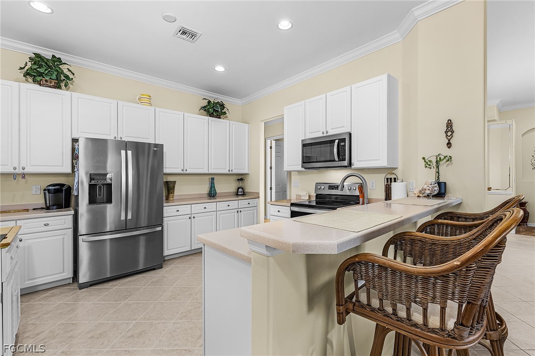 2090 Oxford Ridge Circle Lehigh Acres, FL 33973 - Photo 10 of 27 a kitchen that has a stainless steel appliances a refrigerator a stove a sink a center island and furniture