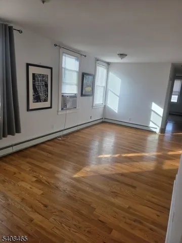 a view of an empty room with window and wooden floor
