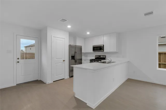 a view of kitchen with stainless steel appliances refrigerator stove microwave and sink