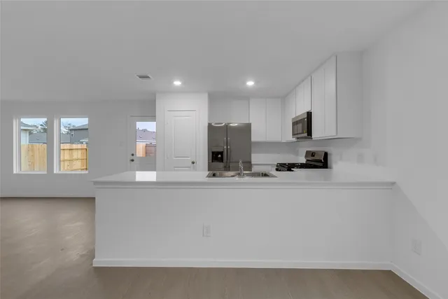 a view of a kitchen with kitchen island a sink wooden floor and counter top space