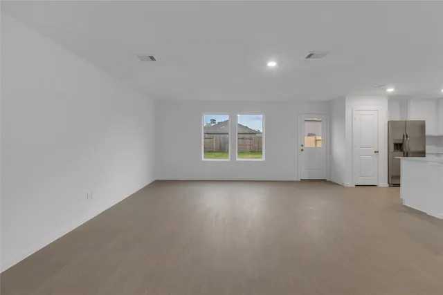 a view of an empty room with a window and a kitchen