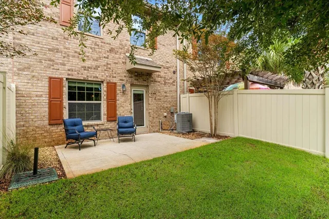 a view of a patio with table and chairs with wooden fence and large trees