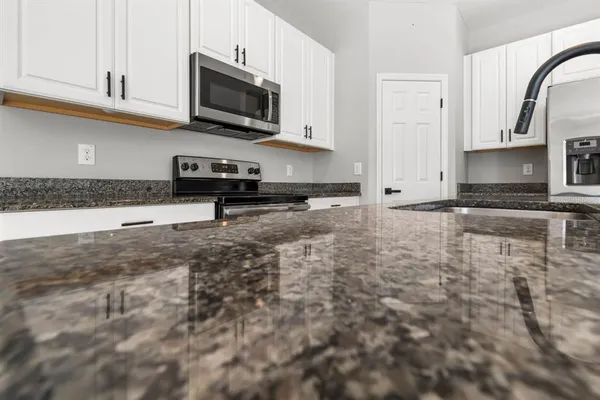 a kitchen with granite countertop a sink a stove a microwave and cabinets