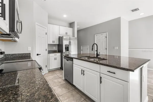 a kitchen with granite countertop a sink stove and cabinets