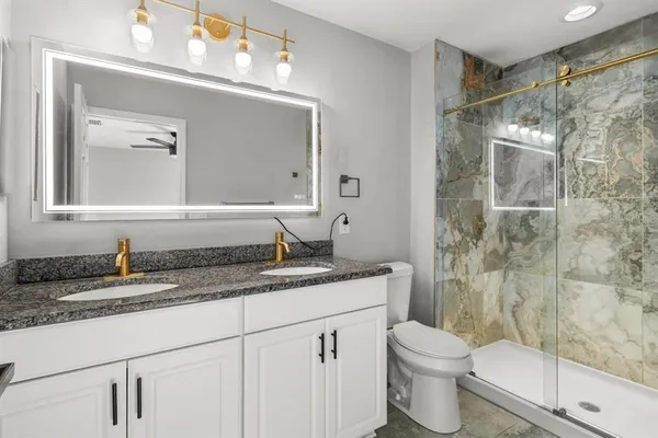 a bathroom with a granite countertop sink mirror toilet and shower