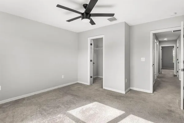 an empty room with closet and a ceiling fan