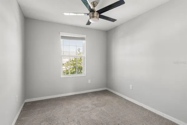 an empty room with a window and a fan