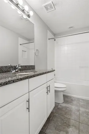 a bathroom with a granite countertop sink mirror vanity and toilet