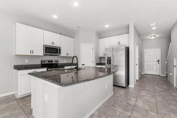 a kitchen with stainless steel appliances granite countertop a refrigerator a sink a stove a microwave and island