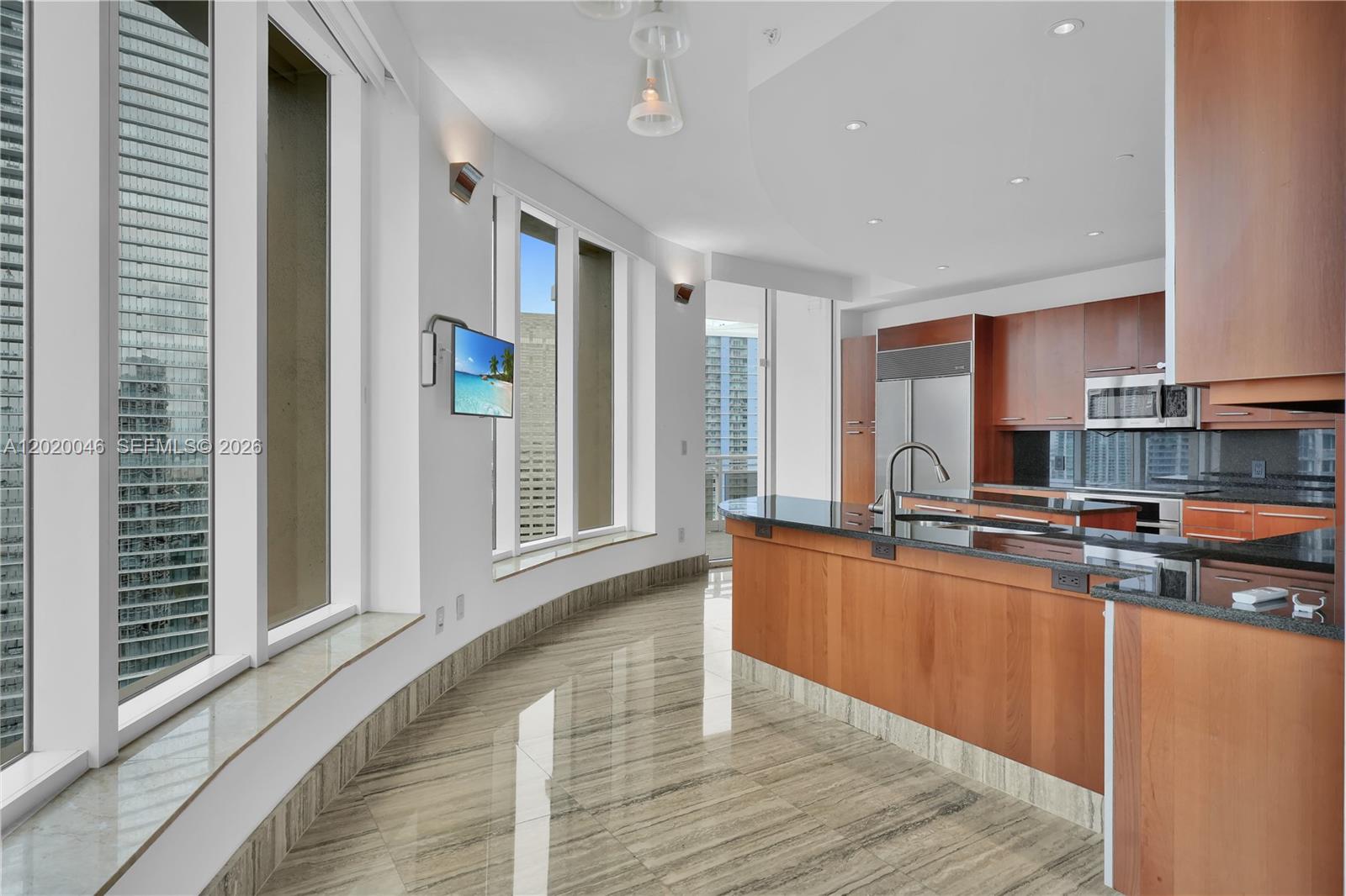 901 Brickell Key Boulevard, Unit 3204 Miami, FL 33131 - Photo 14 of 55 a kitchen with stainless steel appliances granite countertop a refrigerator a sink dishwasher a stove and a dining table with wooden floor